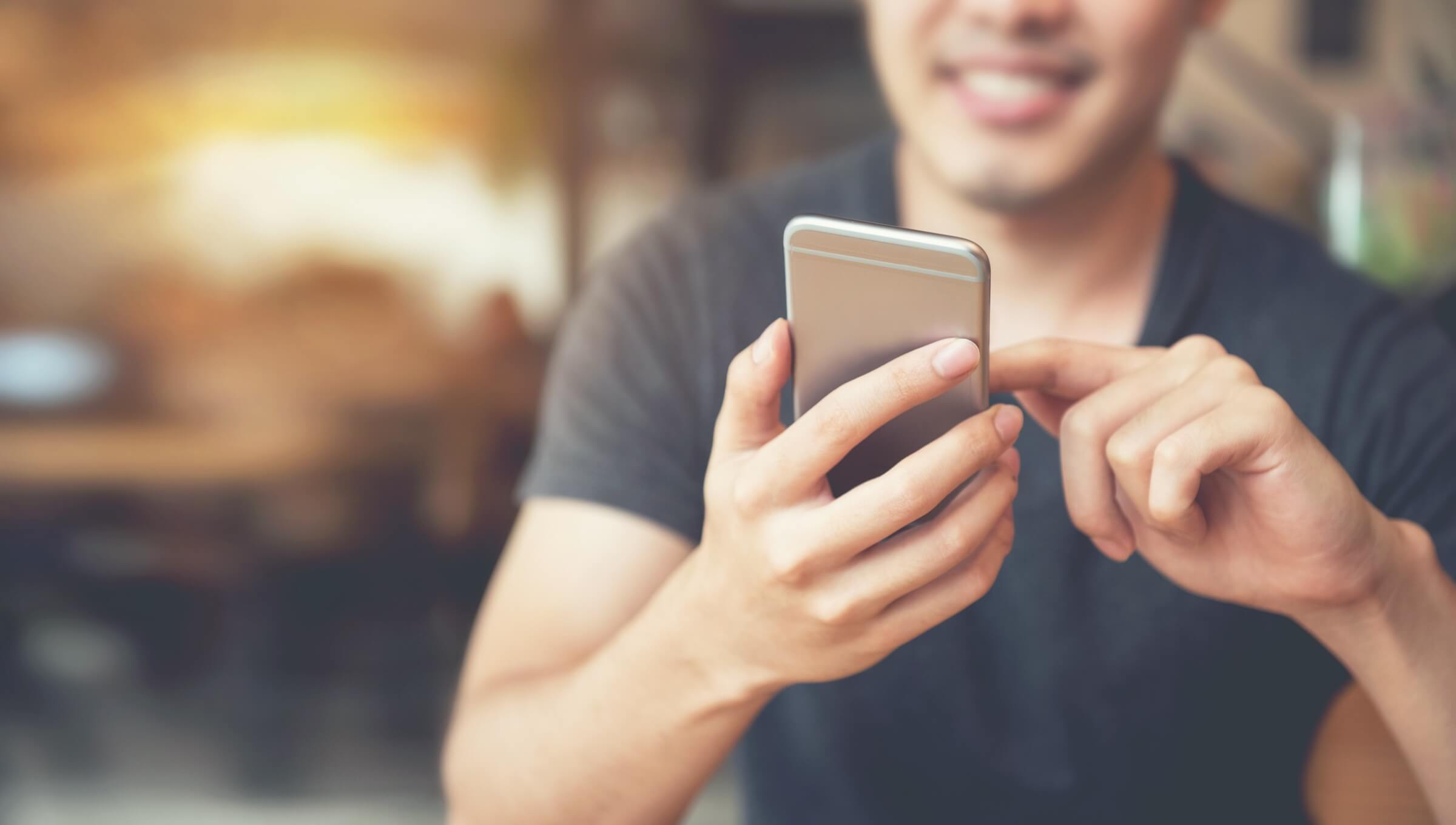 A person smiling while looking using his phone